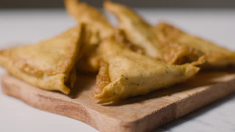 Close-Up-Of-Samosas-On-Wooden-Board-On-Marble-Surface-Celebrating-Muslim-Festival-Of-Eid